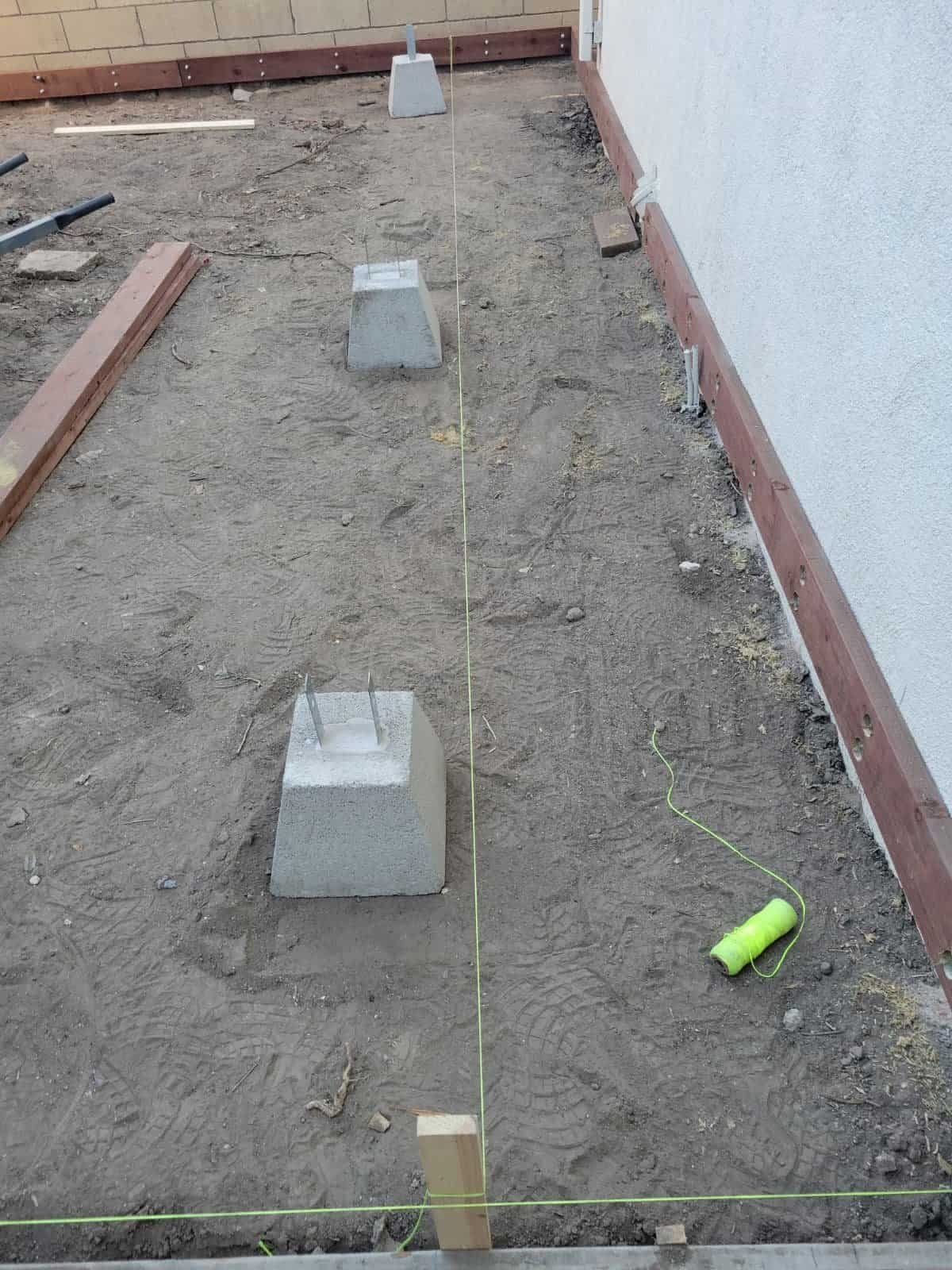 Concrete blocks with metal rebar for foundation marking at a construction site.