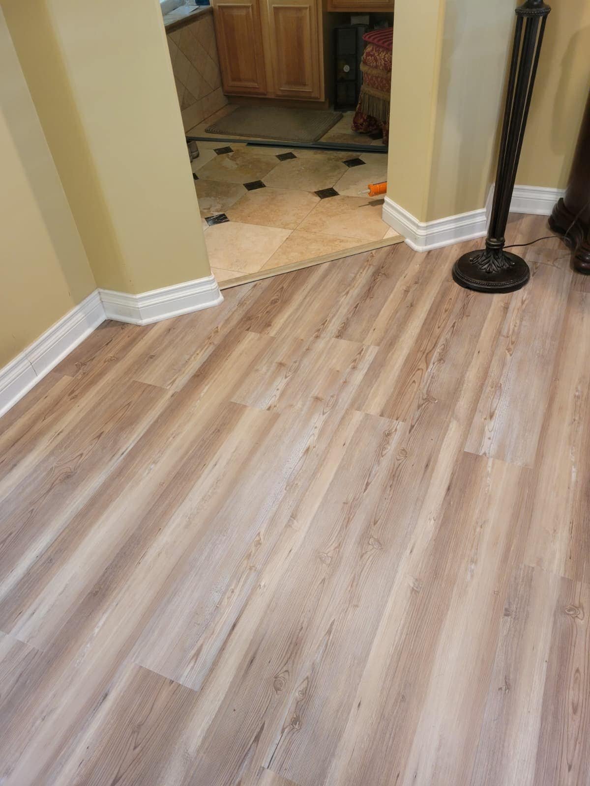 A clean, well-maintained wooden floor leading to a tiled kitchen area, showcasing professional flooring installation and regular maintenance for a polished home environment.