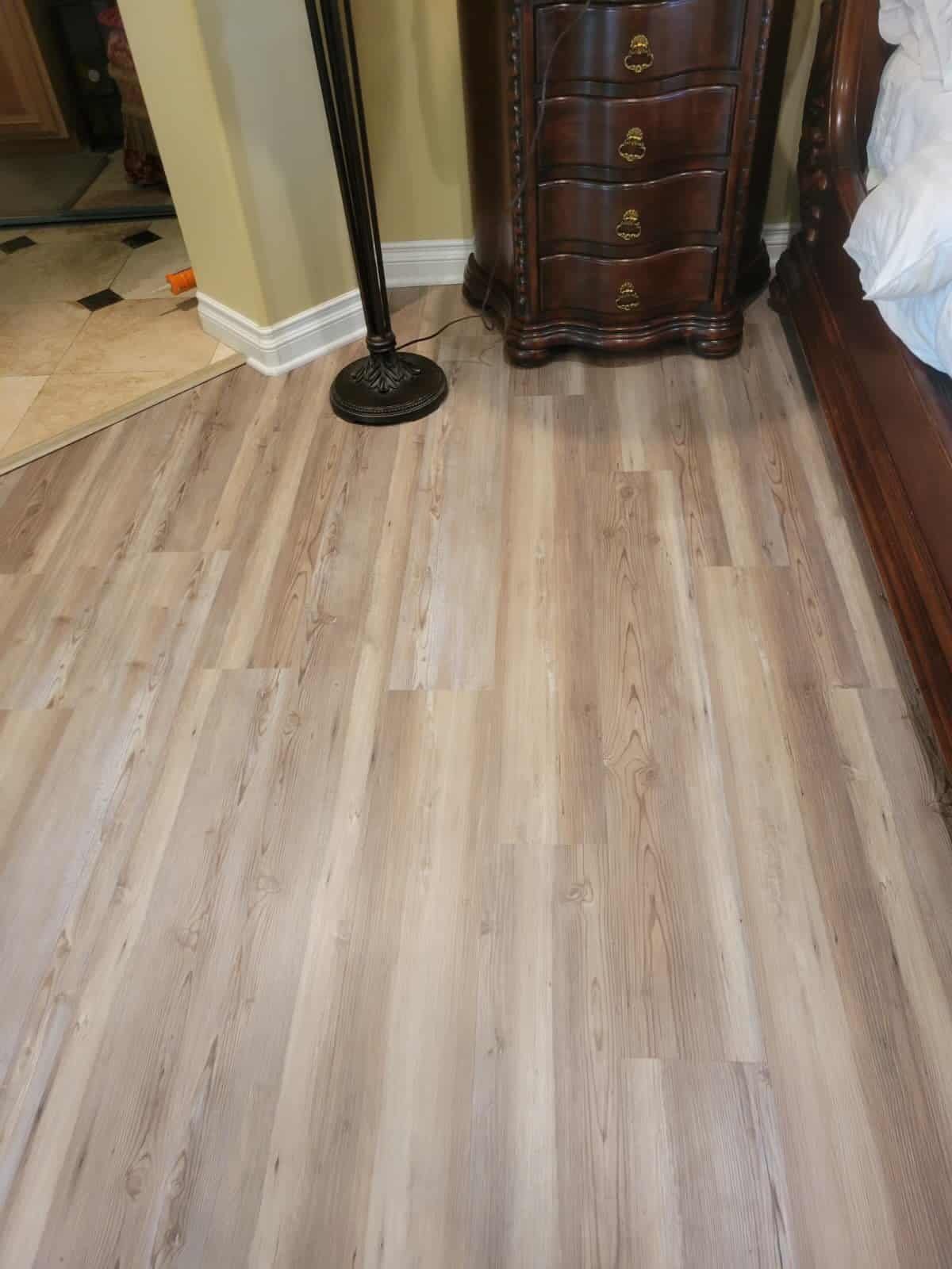 New wood flooring installation in a bedroom with elegant furniture and natural light.