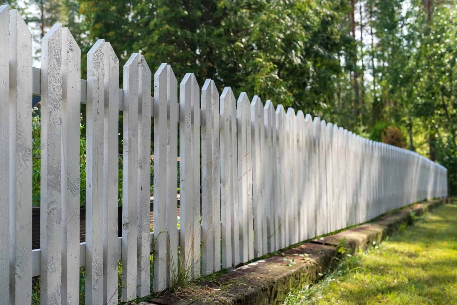 White wooden picket fence with natural outdoor background.